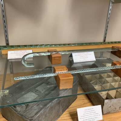 Various Artifacts and Photos Display - Left Side Close Up Bottom Shelves - 2: Various Artifacts and Photos Display - Left Side Close Up Bottom Shelves -2.  Includes glass canes, a glass pipe, Native American Artifacts, egg mailers, and two Troy and New England Railroad Trolley spikes.