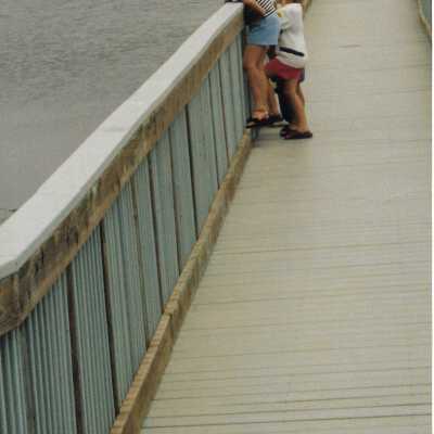 Oso Flaco Lake Bridge with children looking over edge, Photo taken by David Levesque, 1996 - 4" x 11.5" color photograph