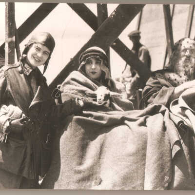 Moses played by Theodore Roberts sits with Mirium played by Estelle Taylor and crew member. Roberts has a scarf layed over his head and Taylor is holding a goat.