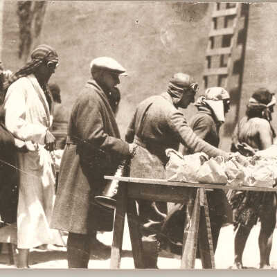 Cecil B. DeMIlle grabbing lunch. Person behind DeMille is carrying his megaphone labeled "Cecil B. DeMille."