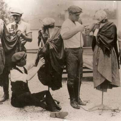 1923 behind the scenes. Costumers touching up costumes on mannequins.