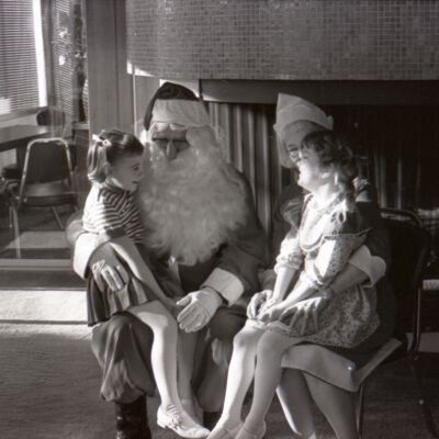Unidentified girls sitting on Mr. and Mrs. Clause's laps, Date unknown: Frame 1f