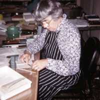 Scan of a slide of Stella Patri working on a sheet of paper