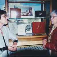 Photo of Stella Patri talking to another in front of a display
