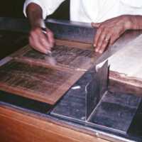Scan of a slide showing a conservator cleaning a page