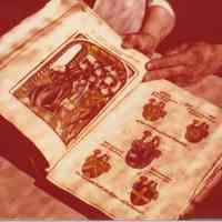 Photo of an open book showing various coats of arms