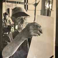 Photo of Ernie Holbeach holding up a sheet of ledger paper