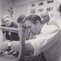 Bookbinding students around a sewing frame, Patri in the background
