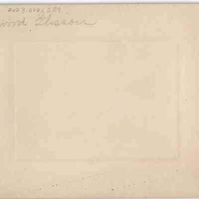 Elwood Glisson in overalls in front of home: back of photograph - "Elwood Glisson"
