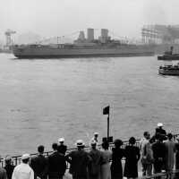 Crowds watch the launching of USS Iowa, afloat for the first time. Note the patrol boat to the right and a tug boat. 80-G-11372.
