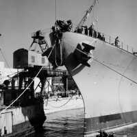Workers continue to position IOWA over her keel blocks. Note size comparison of the boat and IOWA