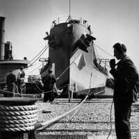 A shipyard worker communicates with the docking crew as IOWA