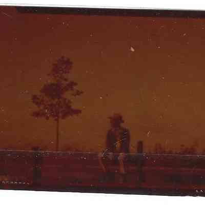 Film Negative of David Read sitting on fence rail