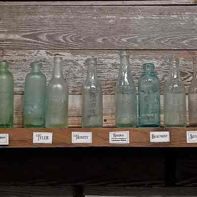 Bottle shelving and bottles showing bottles from various Texas cities