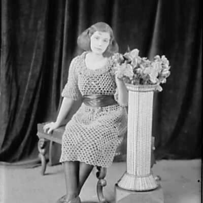 Young Woman Sitting Next to Flower Stand