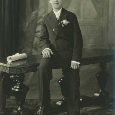 Boy Sitting on Table with Rolled Paper (Diploma?)