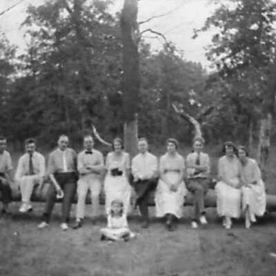 Group of Men and Women Sitting On Log