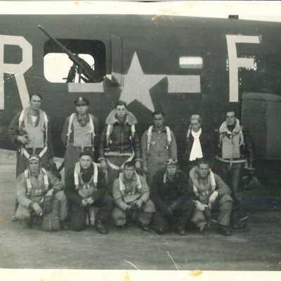 Photo of unidentified WWII Aviators in front of plane with "R" and "F" with a star between the letters on the side of plane