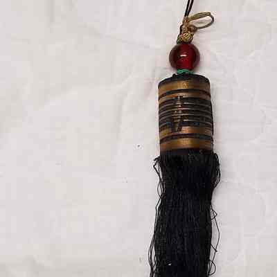Large black tassel with gold accents and red plastic bead