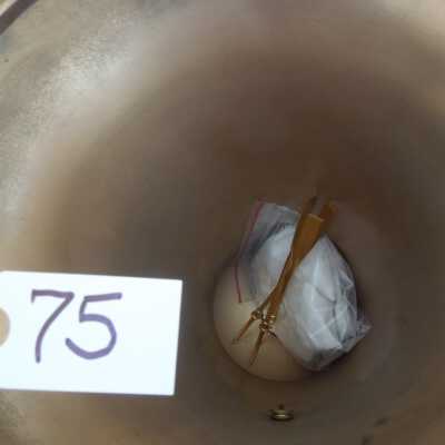 view under base of 075: plastic bag contains 8 plates, and 2 tag/notes on strings (cataloged as Artifact 077)