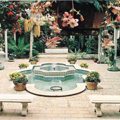 Fountain surrounded by hanging baskets of fuchsias and tuberous begonias