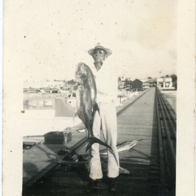 Man in White Outfit Holding Fish