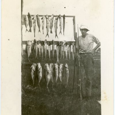 Man Standing Next to Hanging Fish