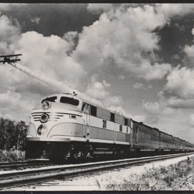 An airplane flying near a Florida East Coast train