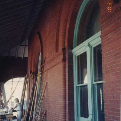 An unknown woman doing some work at a work table on the porch.