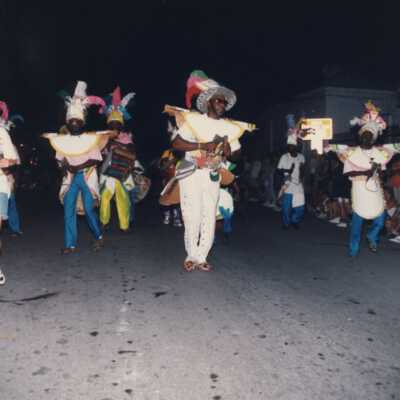 Unknown people dressed up dancing on the street for the parade.