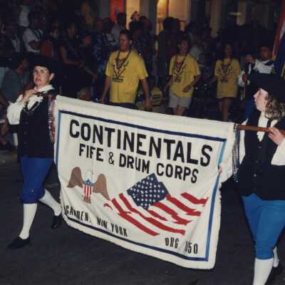 Two unknown people holding a banner that reads Continentals Fife and Drum Corps.