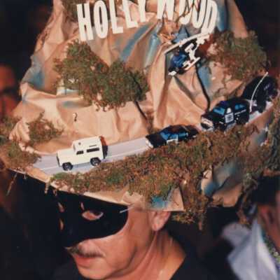 Unknown man dressed up with a head piece on of the Hollywood sign.