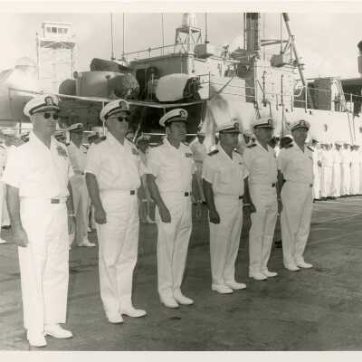 Men in uniform standing next to a Navy ship