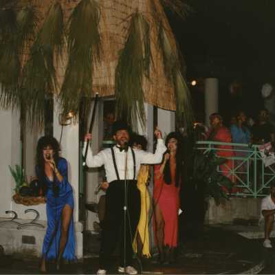 Unknown people dressed up on a stage singing.