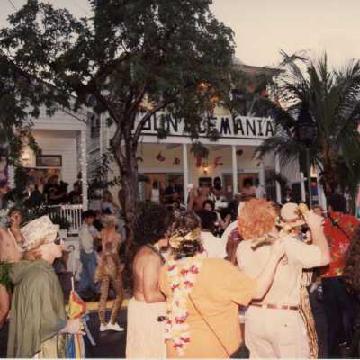 Unknown people walking and standing on the street, many are dressed up.