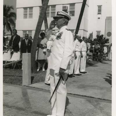 An unknown man saluting with a group in the back ground