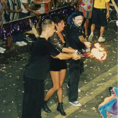 Three unknown people dressed up juggling in the street for the parade.