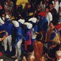 A group of unknown people dressed up walking in the street.