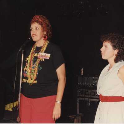 Unknown woman on a stage, one is talking into a microphone.