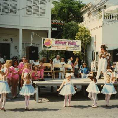 A group of unknown kids dancing in front of a stage.