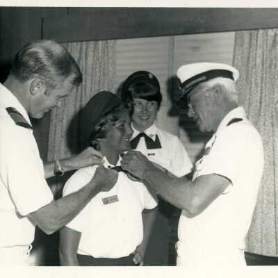 Men in uniform helping 2 woman in uniform