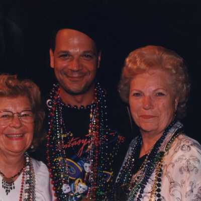 Two unknown woman standing with an unknown man.