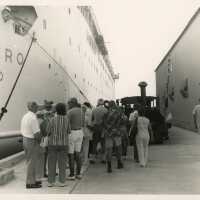 A group of Unknown people on the pier in between 2 Navy ships