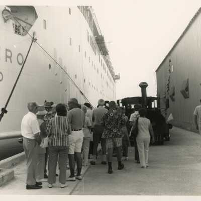 A group of Unknown people on the pier in between 2 Navy ships