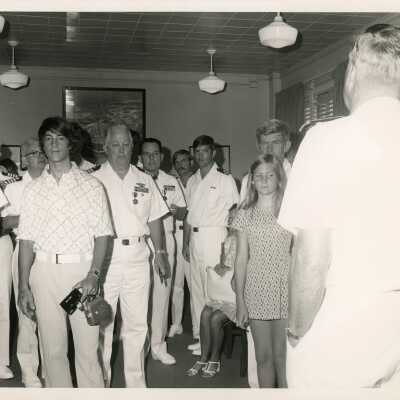 A group of U.S. Military men with unknown people standing in a room
