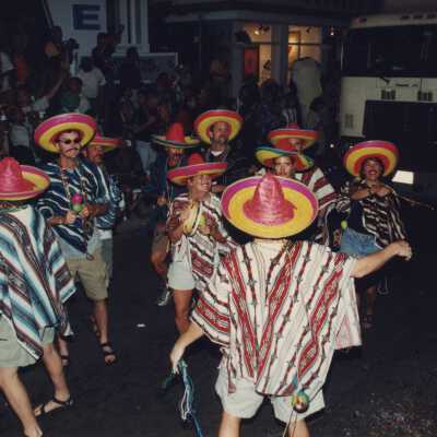 Unknown people dressed up dancing on the street for the parade.
