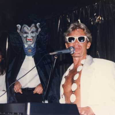 Unknown man playing the piano and singing into a microphone on a float.