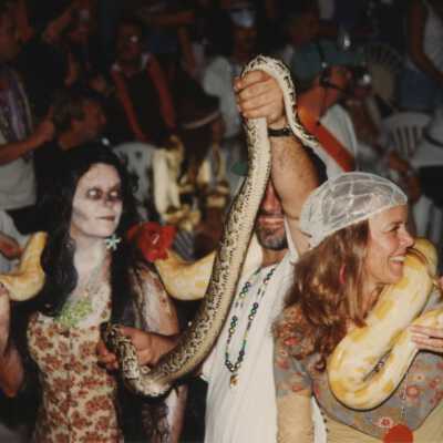 Unknown people walking in the parade holding snakes.