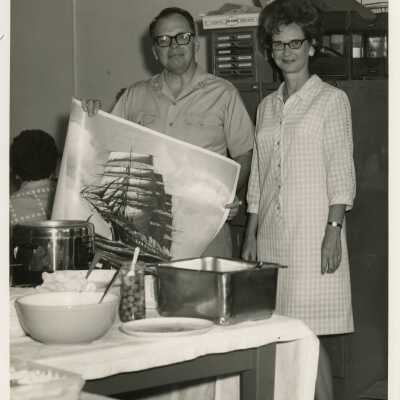 An unknown lady and man holding up artwork at a party