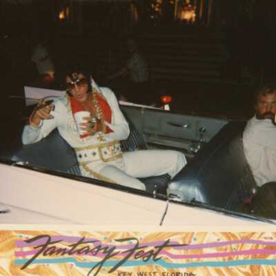 Someone dressed up as Elvis in a convertible car.